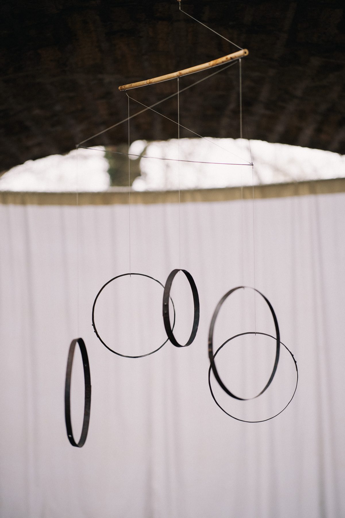Wine cask hoops suspended in front of a white curtain