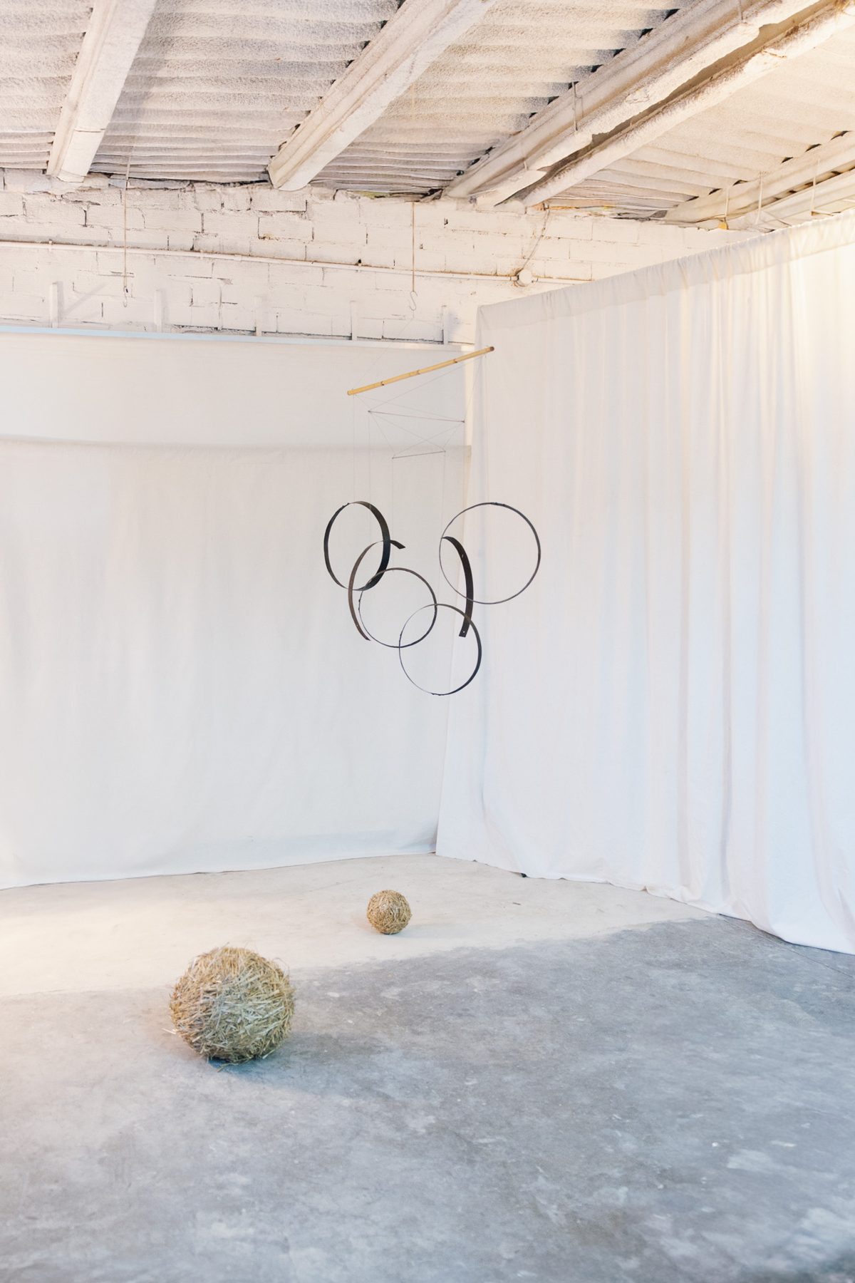 Wine cask hoops mobile and straw spheres in a white room